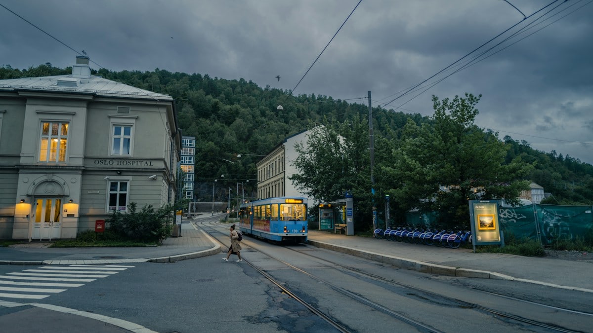 a blue and yellow bus driving down a street next to a tall building